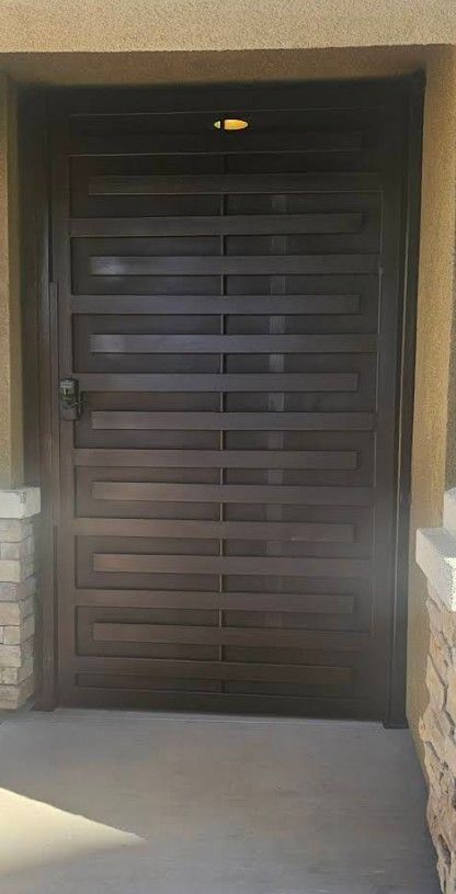 Brown metal security door with horizontal bars, set in a tan doorway.