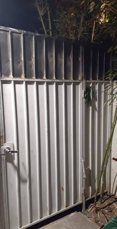 White metal gate with vertical lines, dark smoke marks at the top, and a bamboo backdrop.