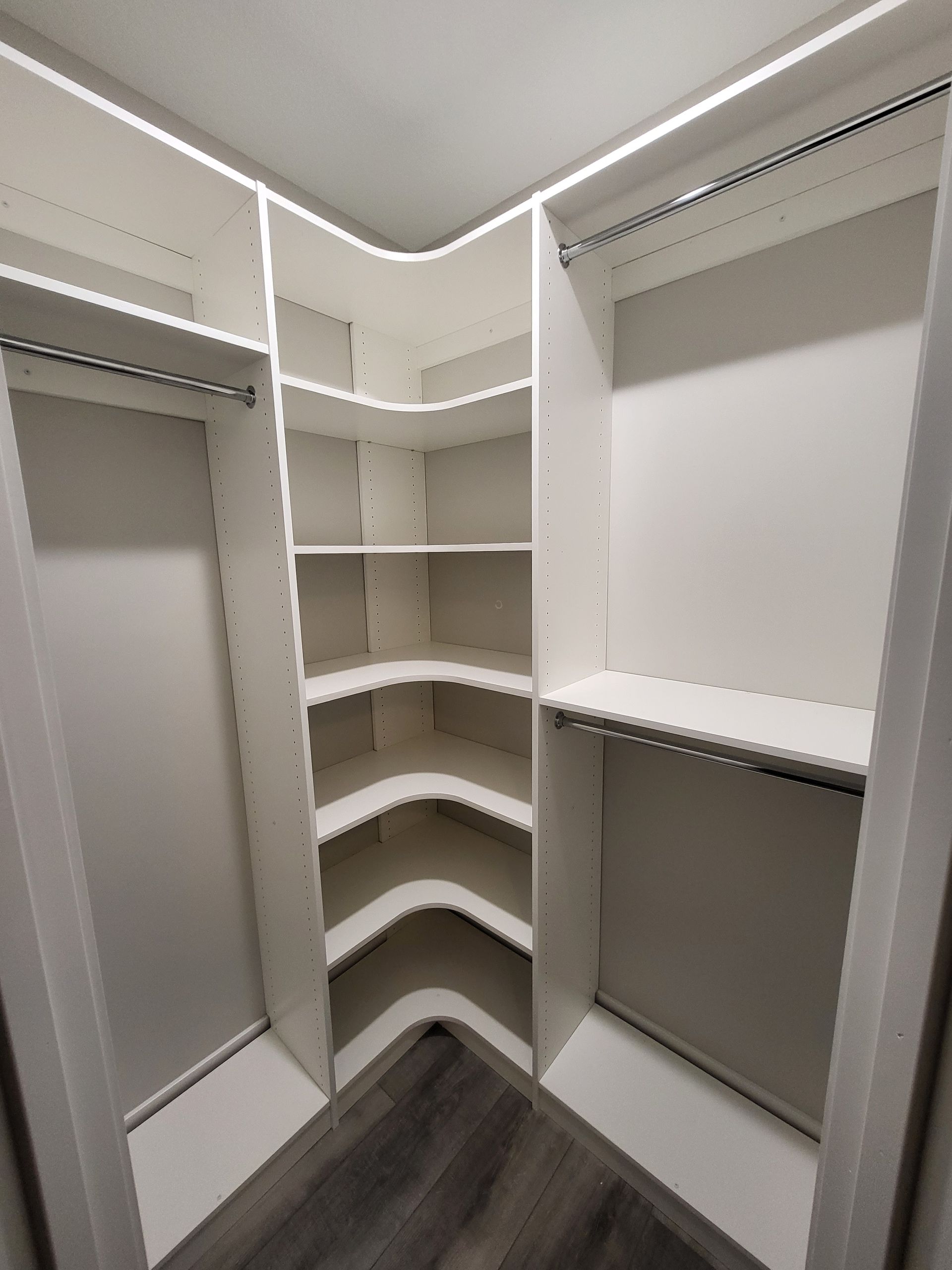 A walk in closet with a lot of shelves and hanging clothes.