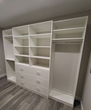 A walk in closet with lots of shelves and drawers.