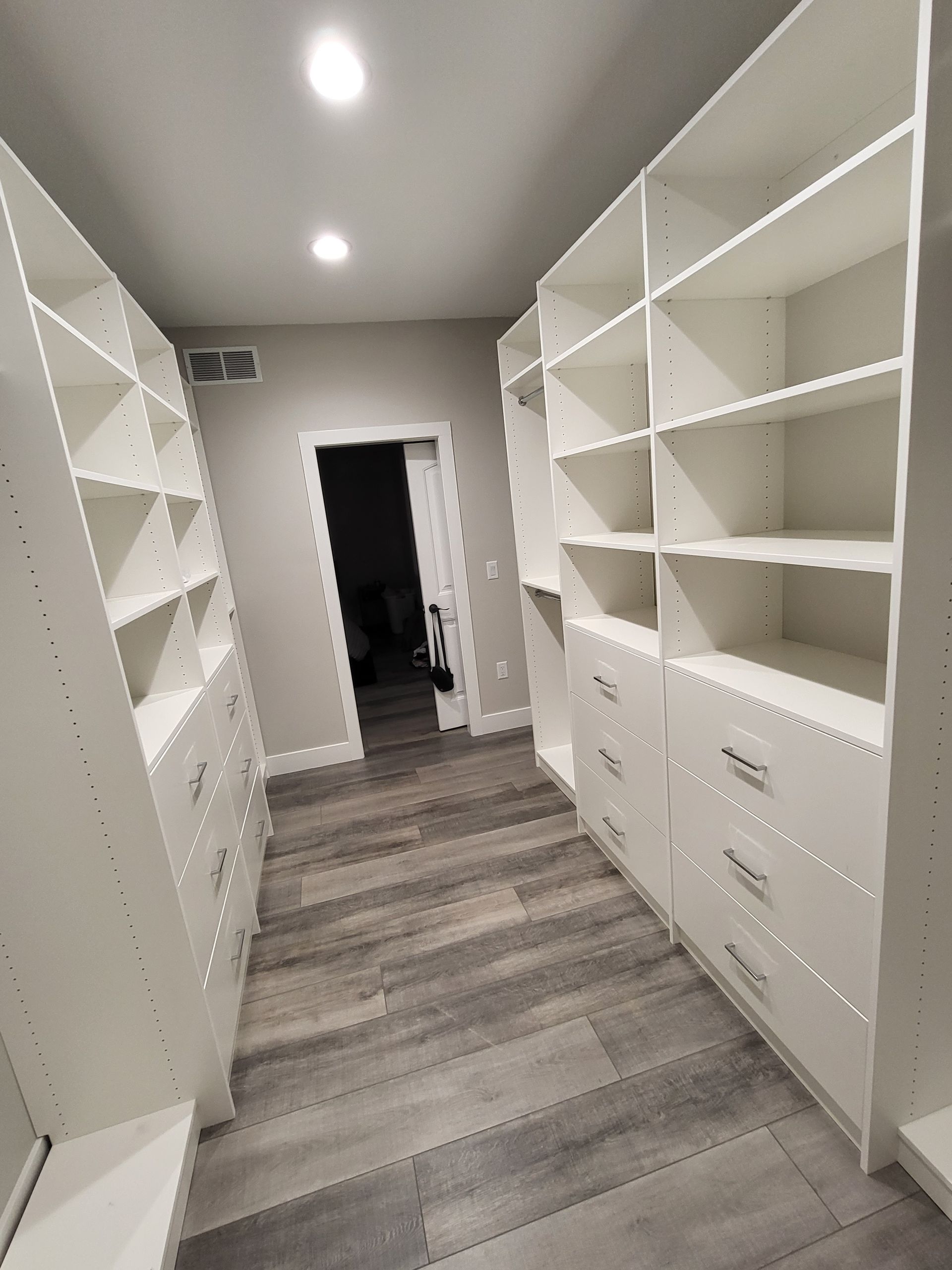 A walk in closet with lots of shelves and drawers.