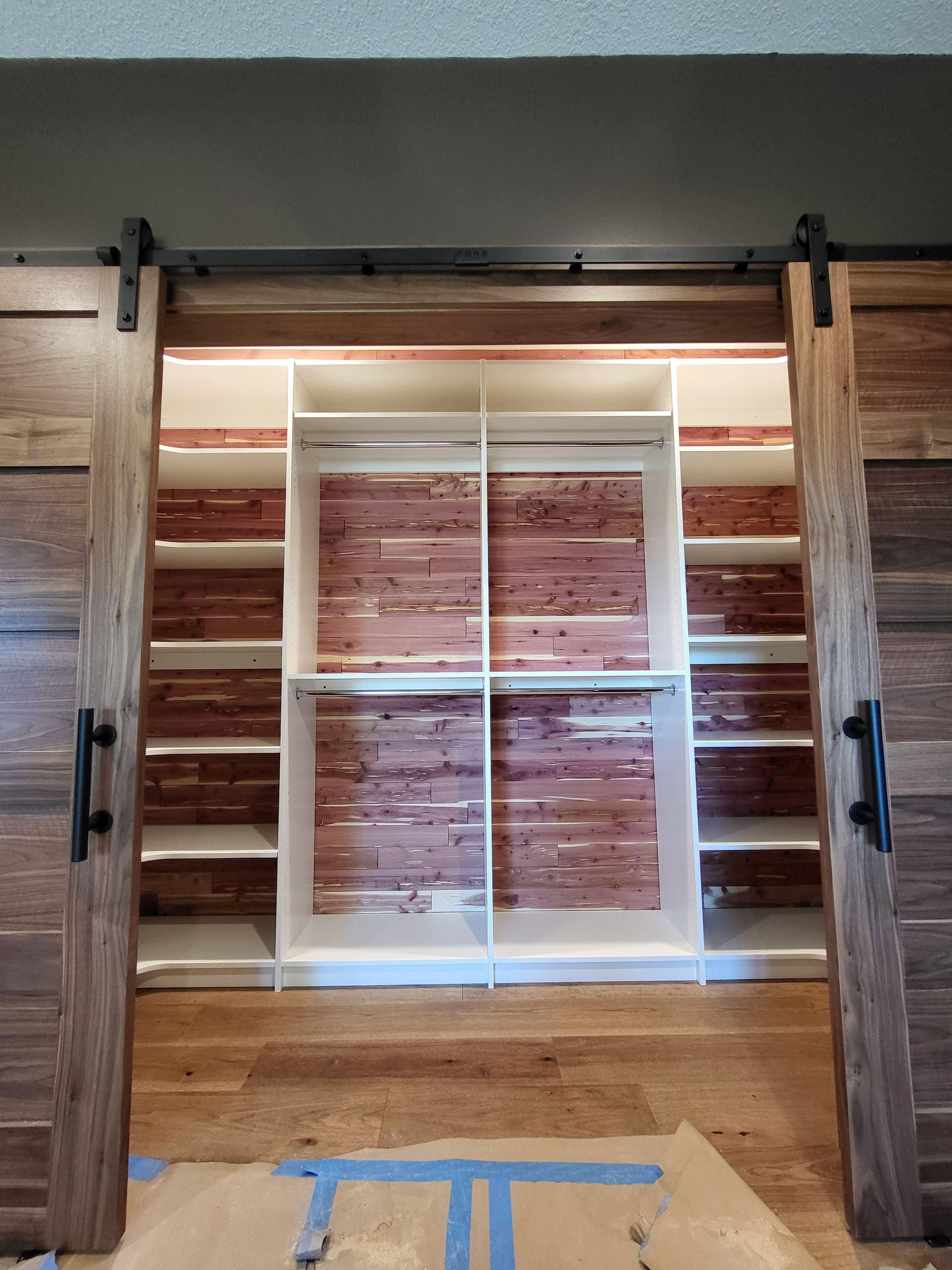A brick wall is behind a closet with sliding barn doors