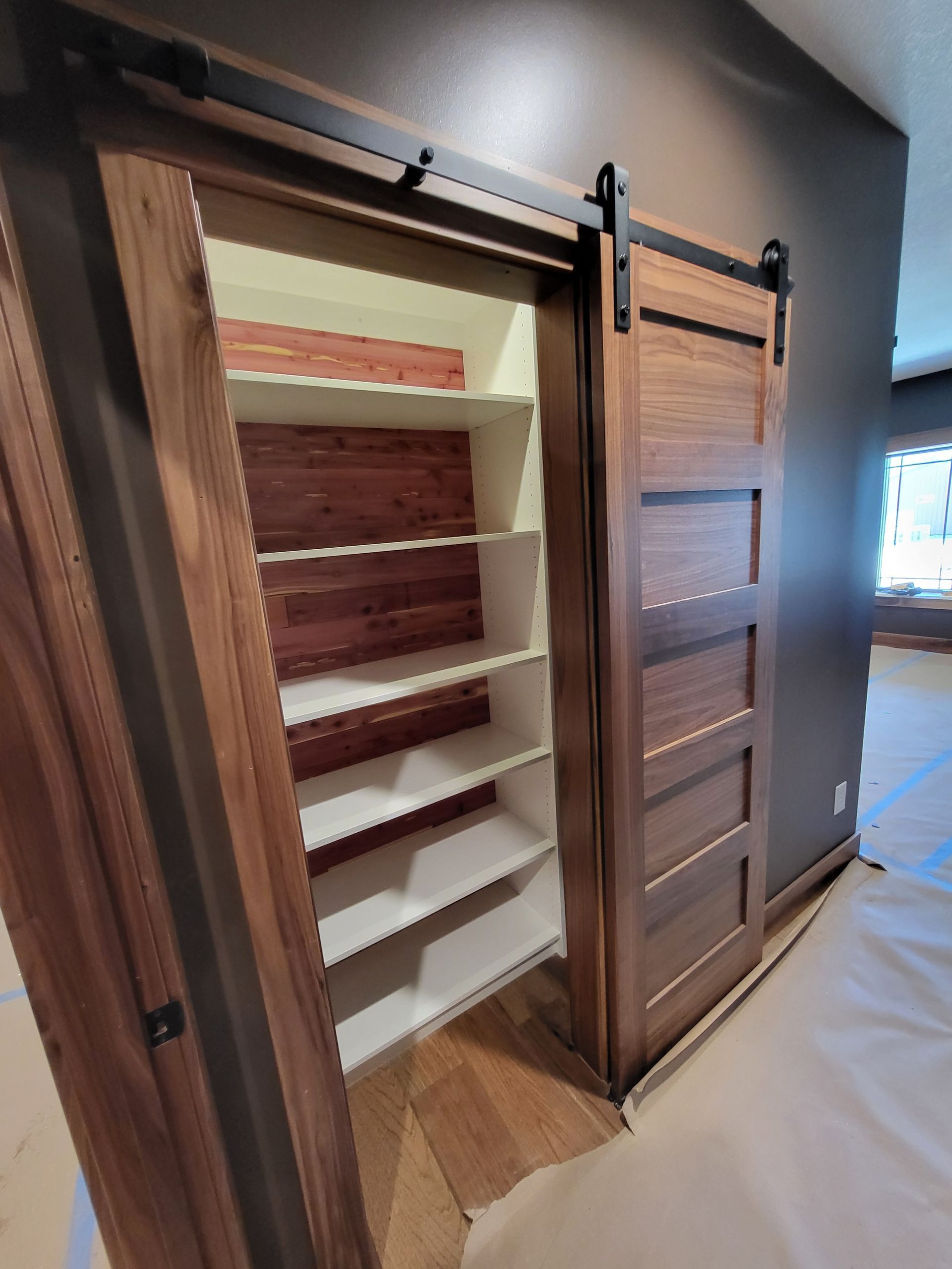 A sliding barn door is open to a closet with shelves.