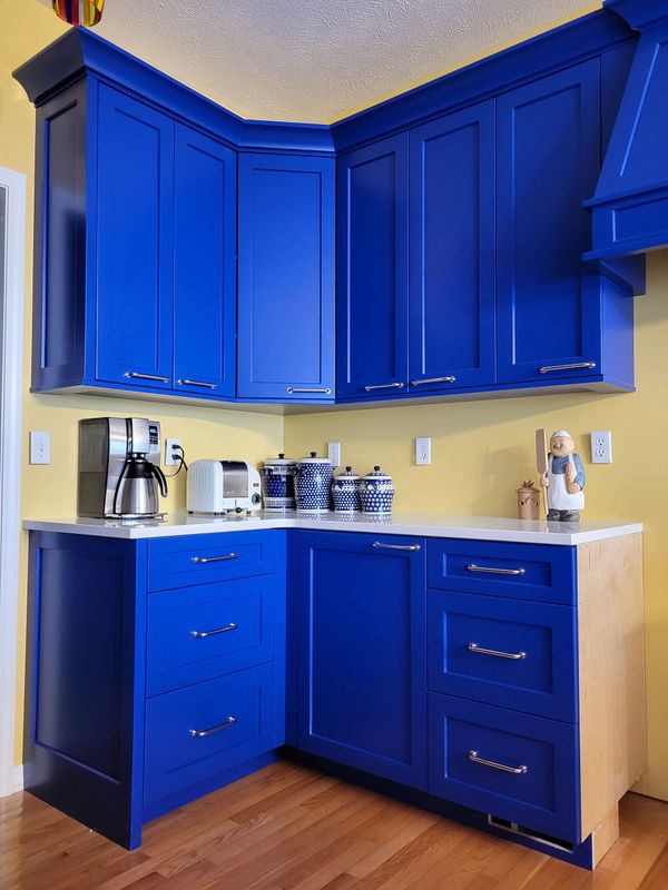 A kitchen with blue cabinets and a coffee maker