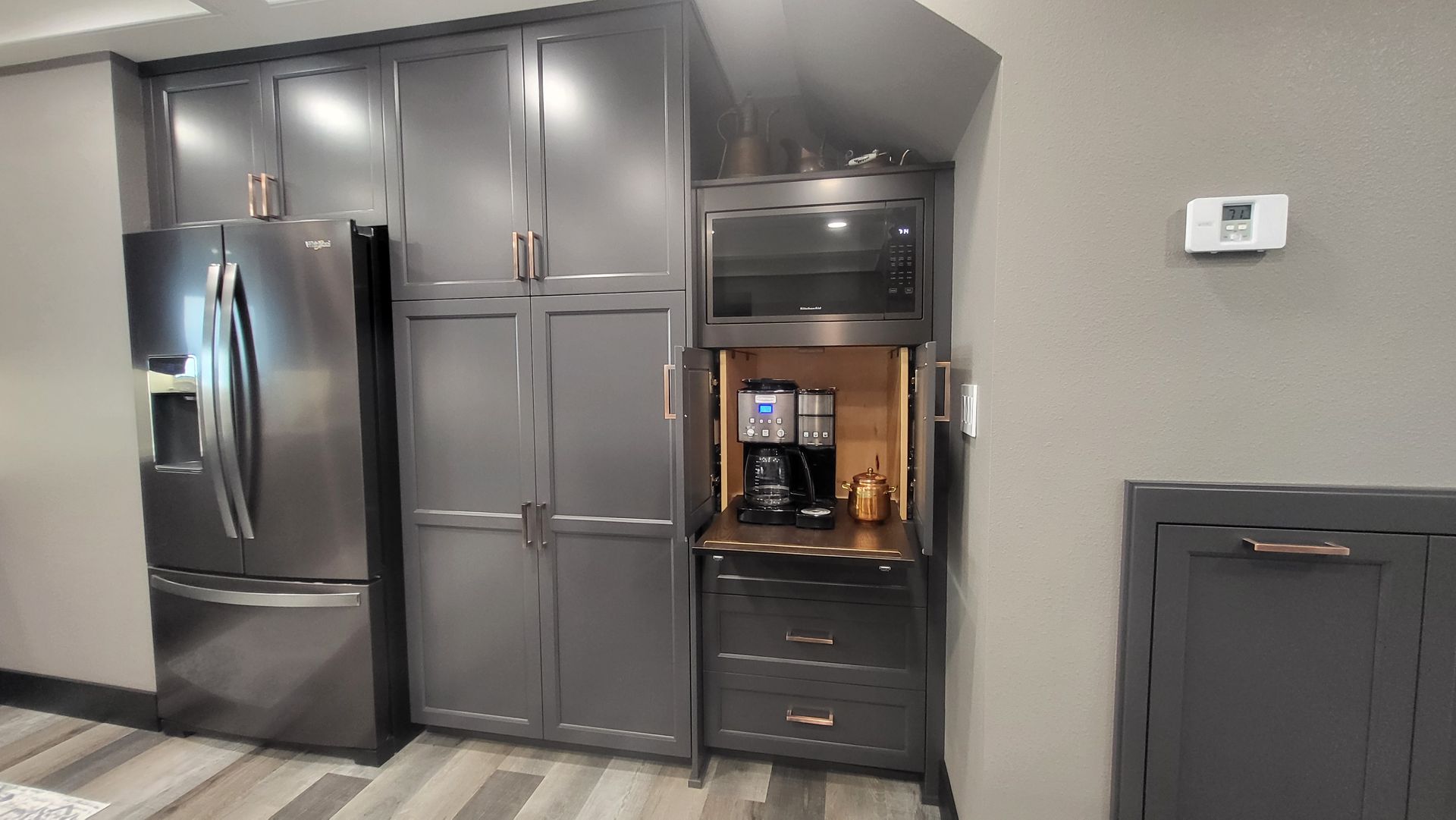 A kitchen with a refrigerator , microwave , and coffee maker.