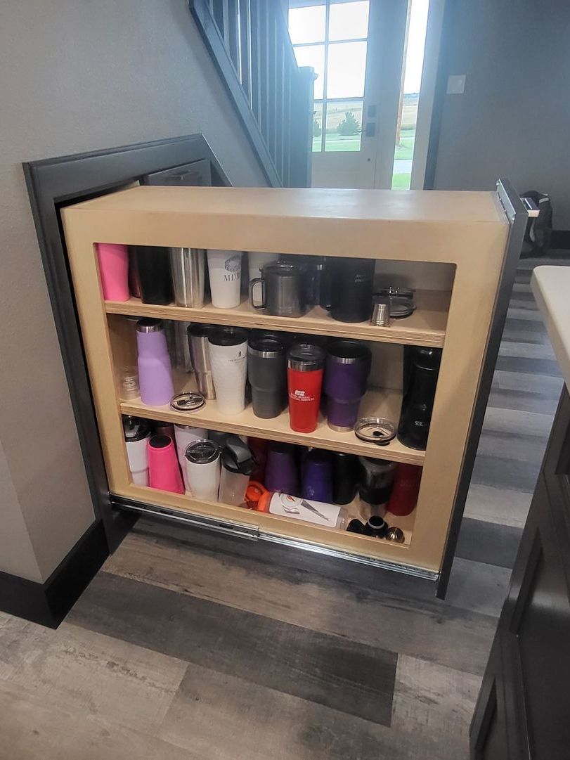 A wooden shelf filled with a variety of cups and bottles.