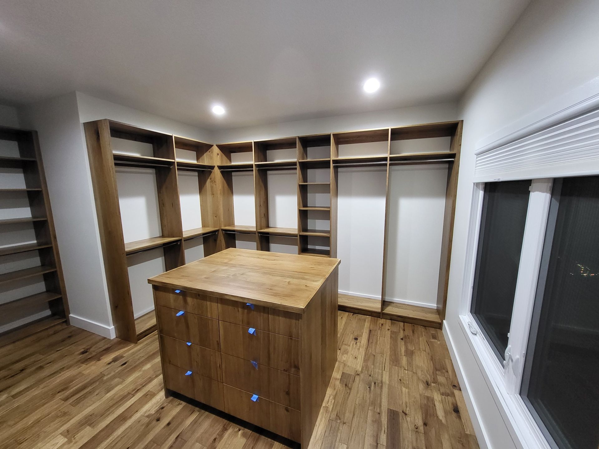 A walk in closet with lots of shelves and a large island in the middle.