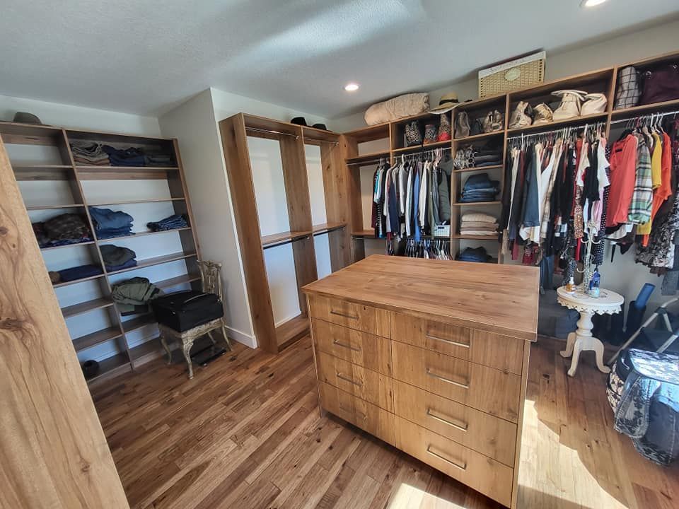 A walk in closet filled with lots of clothes and a large wooden island.