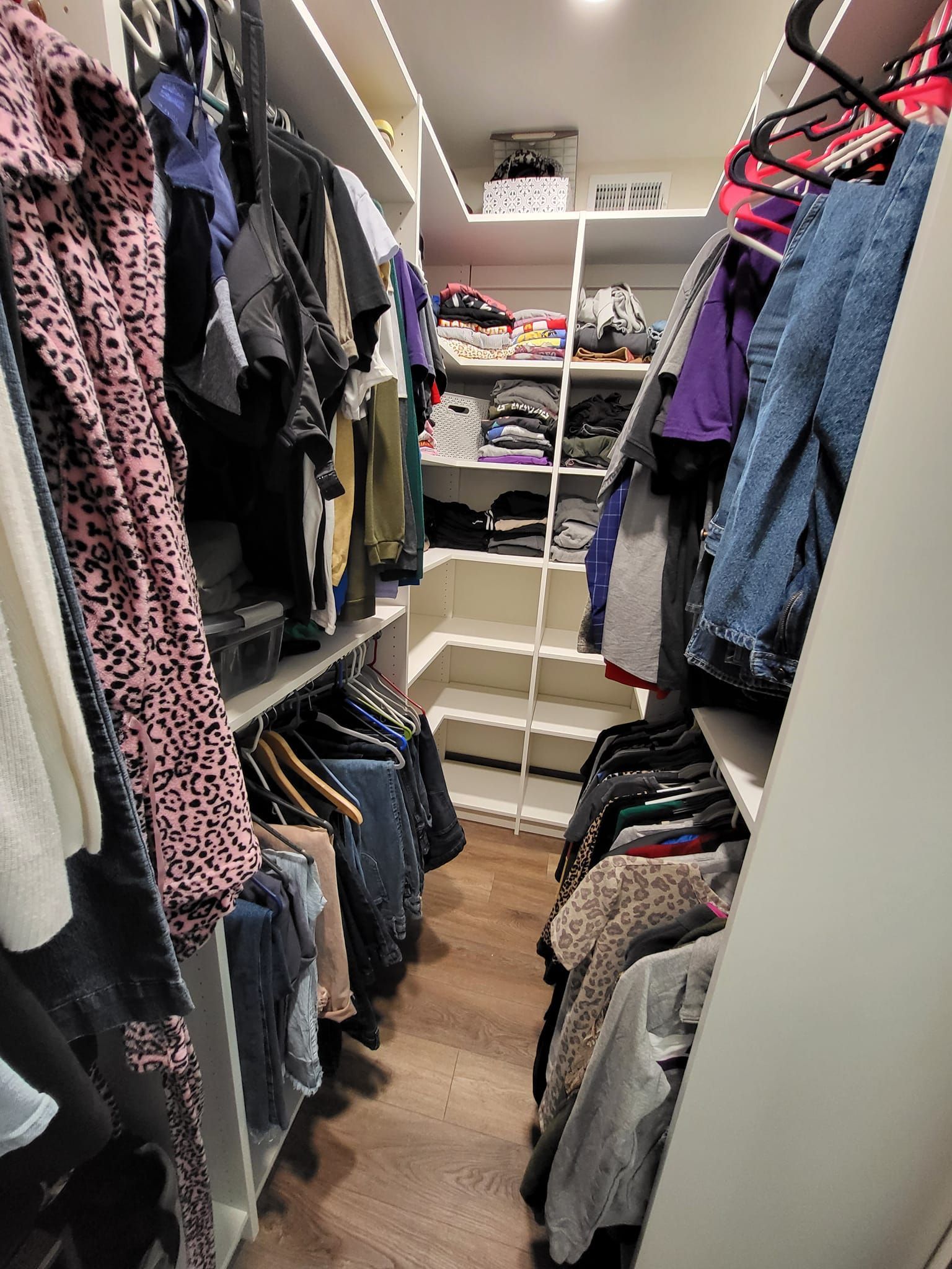 A walk in closet filled with lots of clothes and shoes.