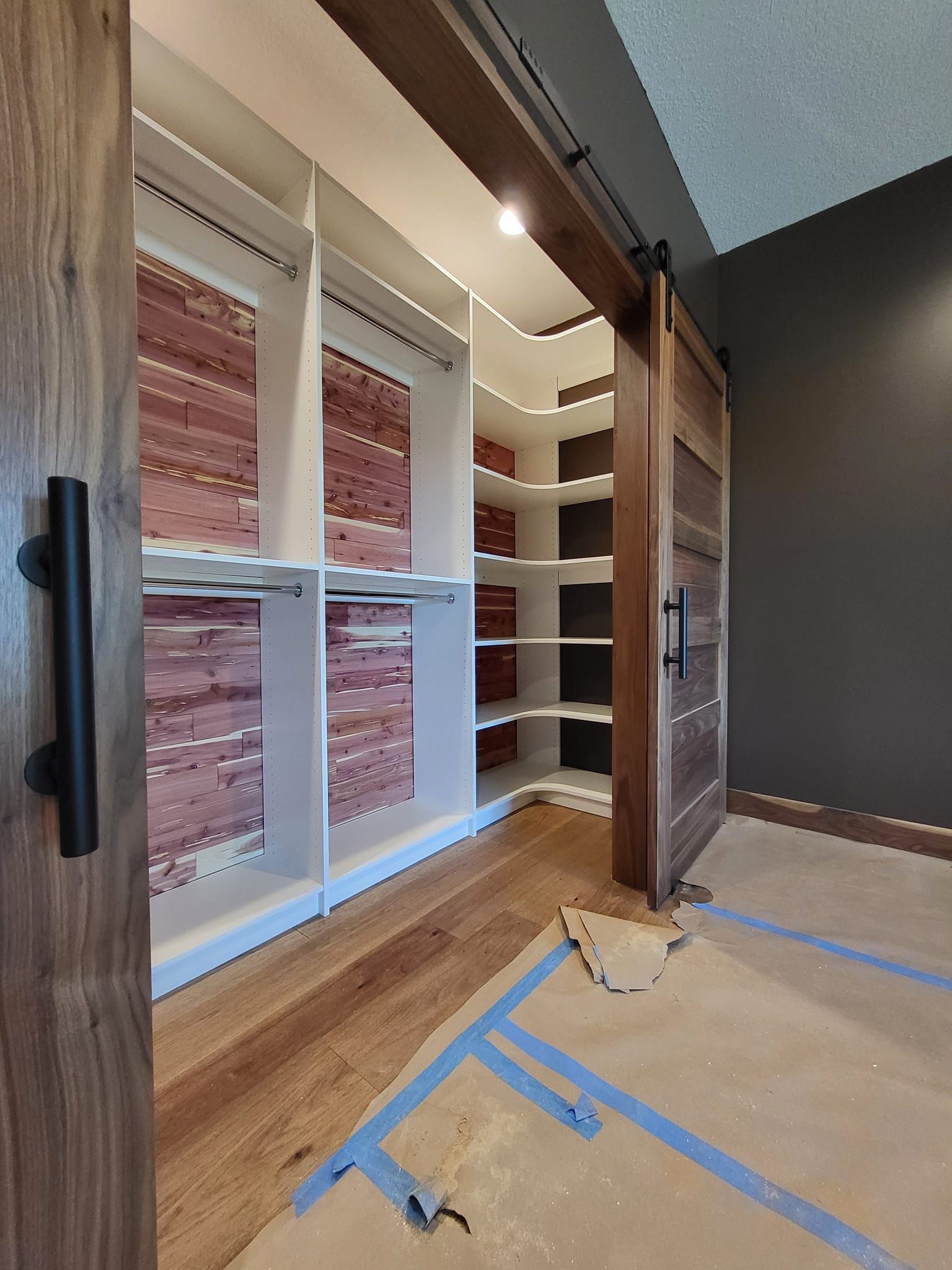 A walk in closet with a sliding barn door and brick walls.