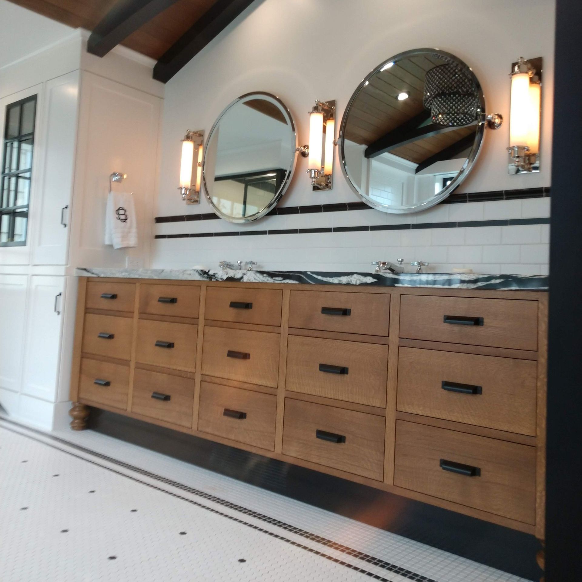 A bathroom with two round mirrors and lots of drawers