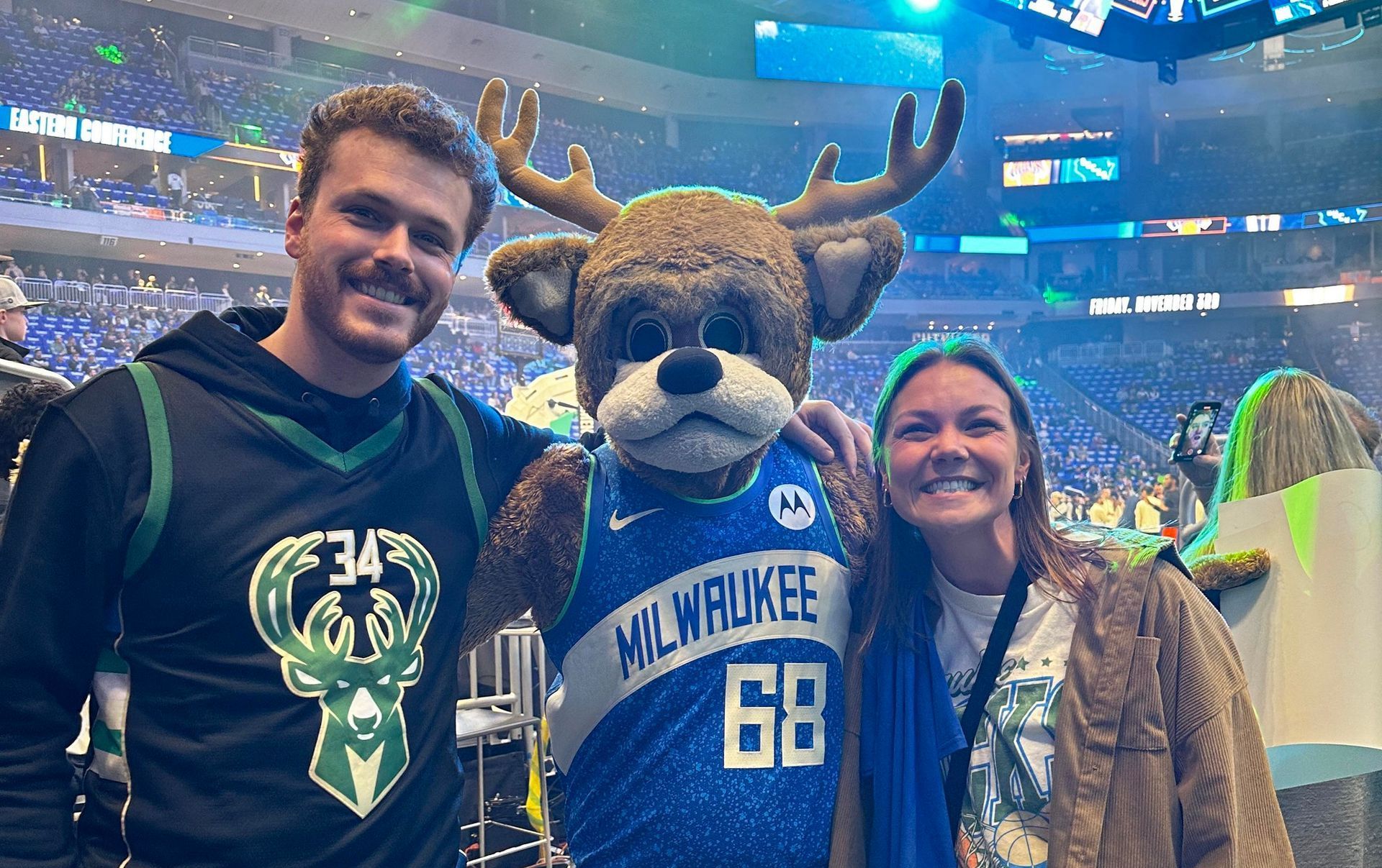 A man and a woman are posing for a picture with a milwaukee mascot.