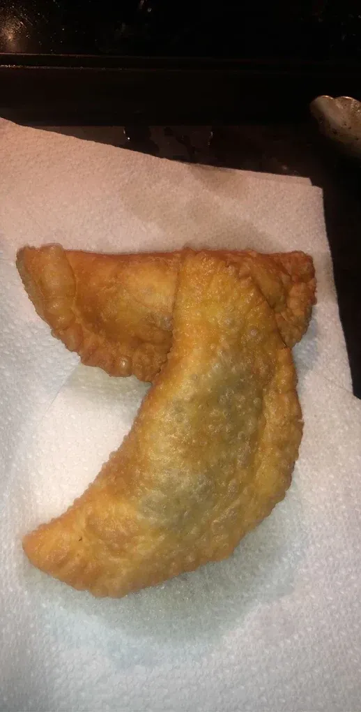 Two golden-brown fried pastries on white paper towel; close up.