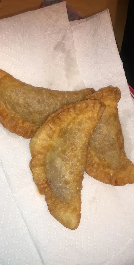 Three golden-brown fried pastries on a white paper towel.