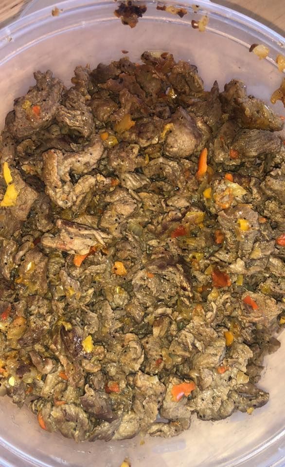 Overhead view of a bowl of cooked meat and vegetables, speckled with orange and yellow pieces.