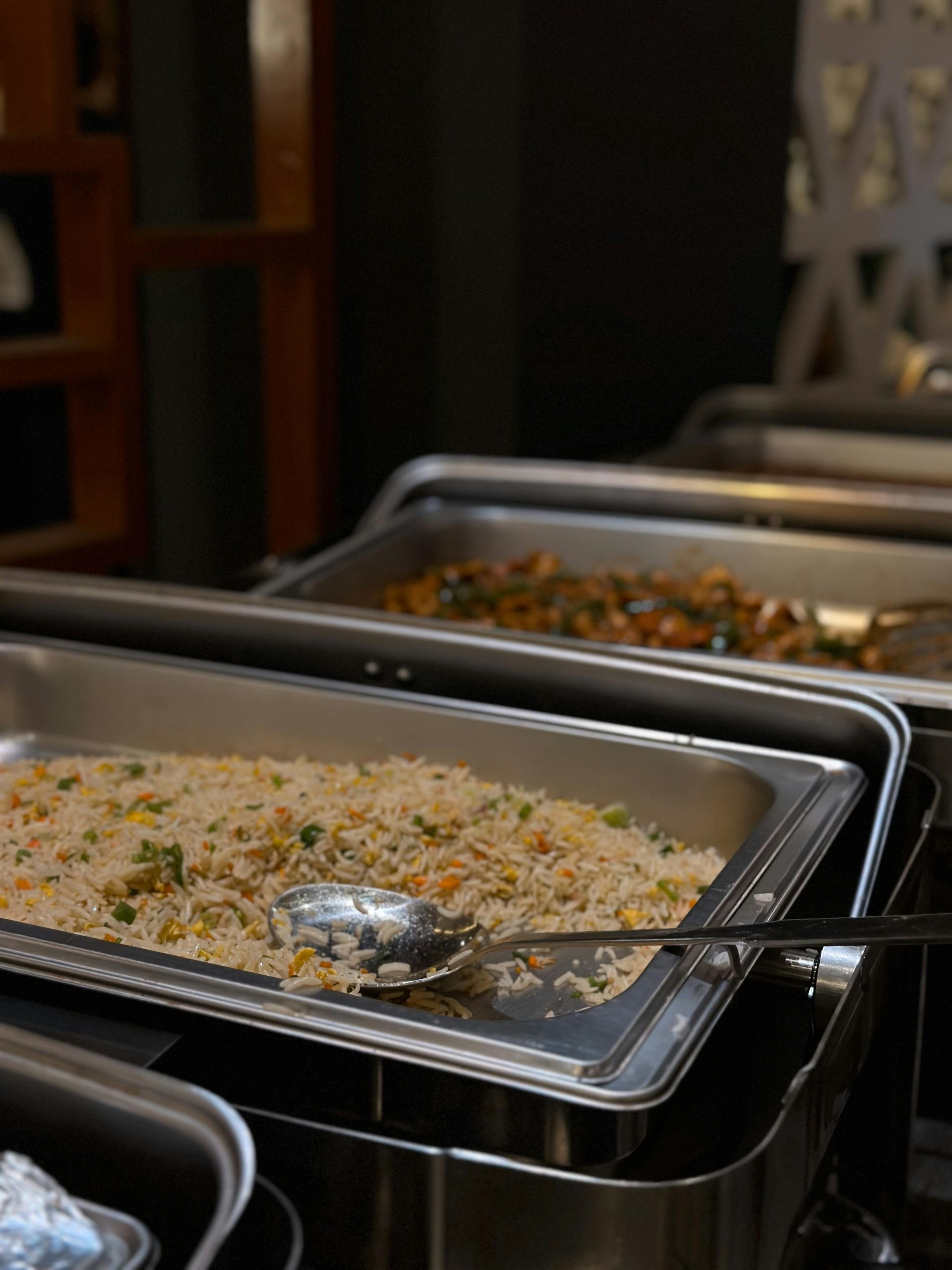 Buffet serving trays filled with food, including rice and vegetables.