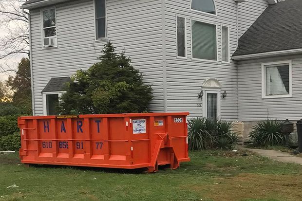 A large red dumpster is parked in front of a house.