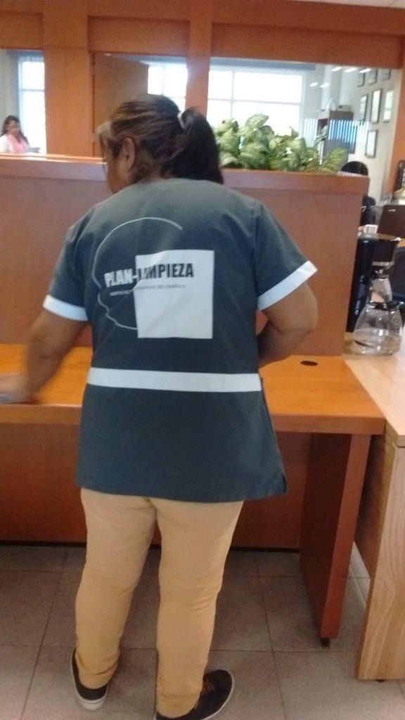 Una mujer está parada frente a un escritorio en una oficina.
