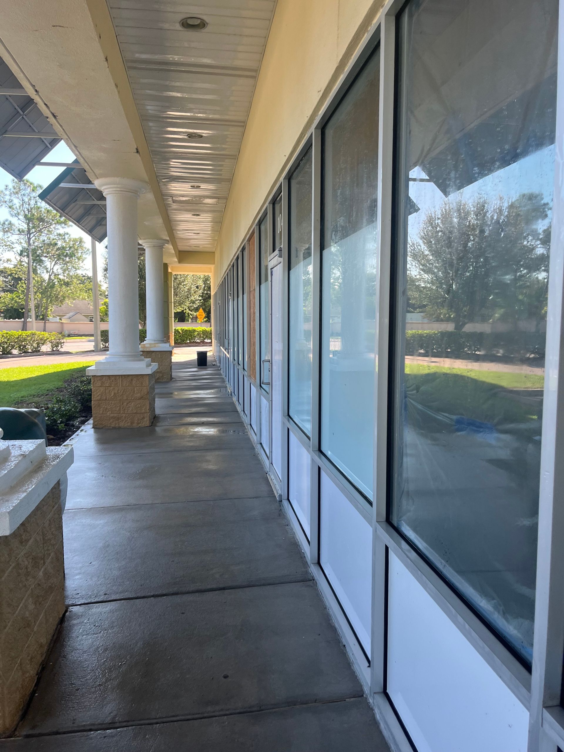 Exterior view of a building with a long hallway, windows, and white columns.