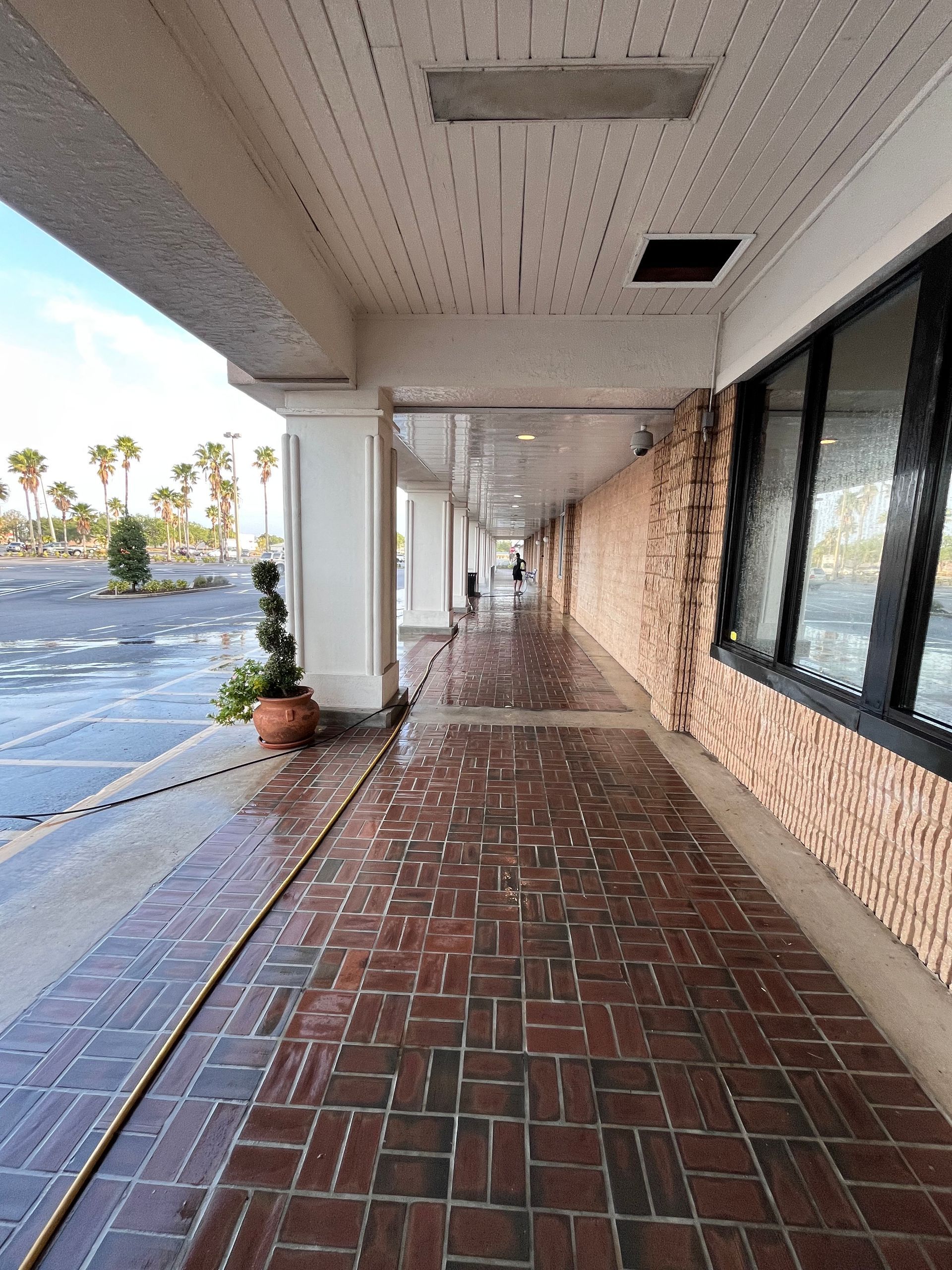 Covered walkway with red brick floor, brick and white columns.