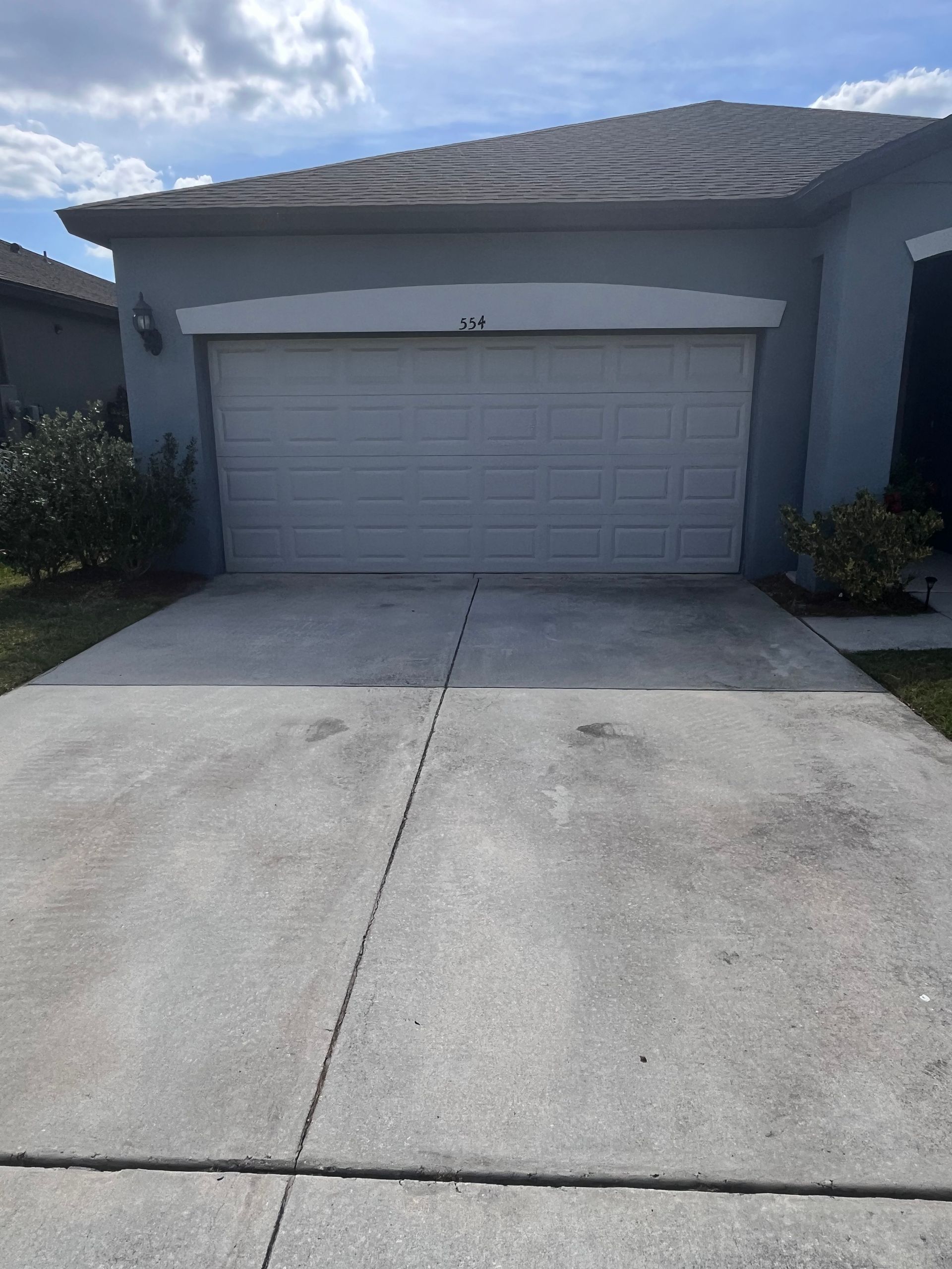 A gray house with a closed garage door and a concrete driveway.