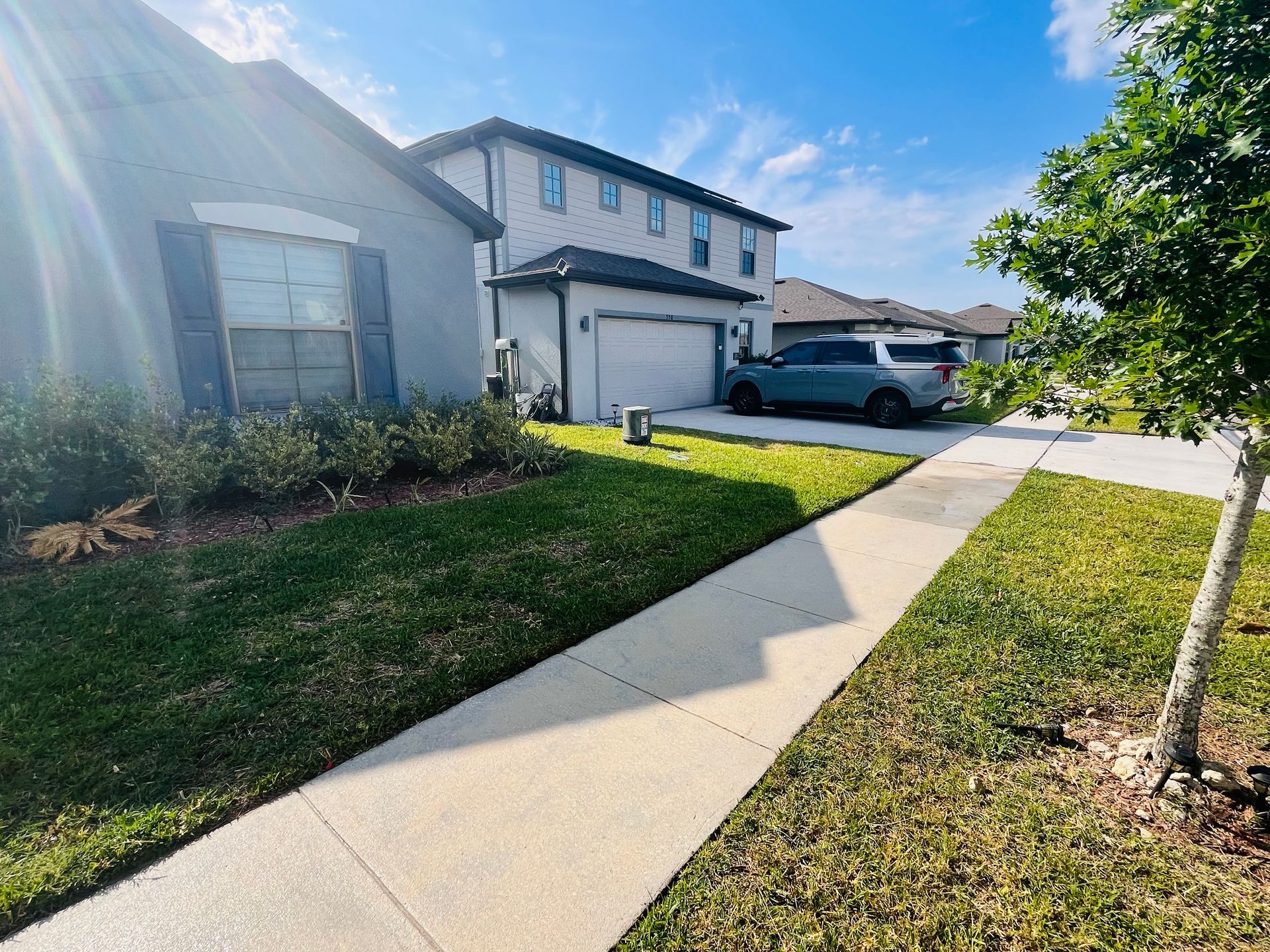 Suburban home with gray siding, a car parked in the driveway, and a sidewalk.