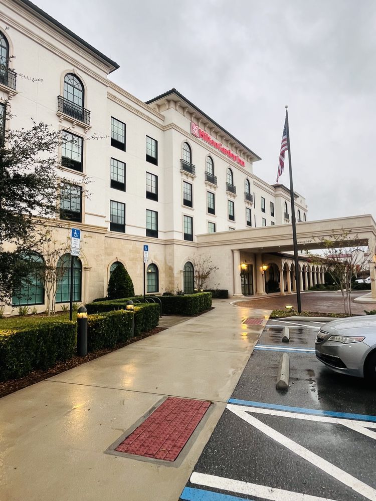 Exterior view of a white, multi-story hotel with a covered entrance, American flag.
