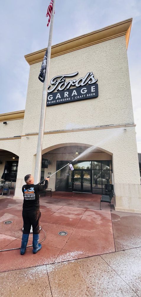 A person power washing the exterior of Ford's Garage restaurant. They are spraying the ground and building facade.