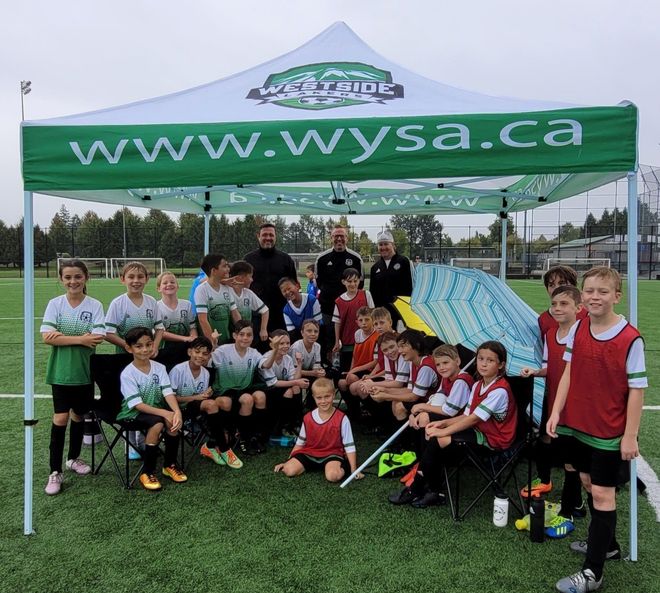 A group of children are posing for a picture under a canopy that says www.wysa.ca