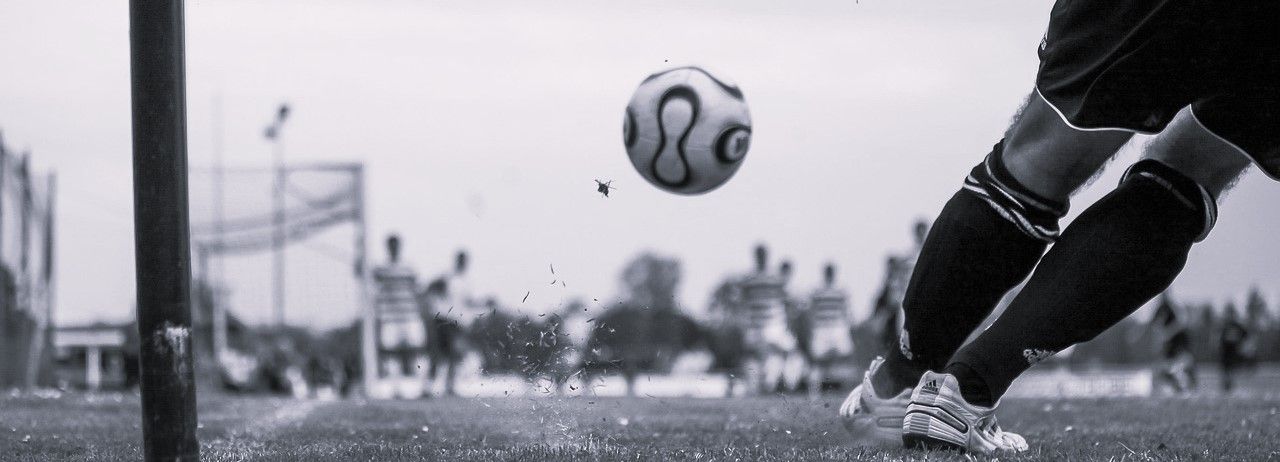 A soccer player is kicking a soccer ball in a black and white photo.