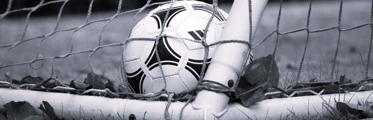 A black and white photo of a soccer ball in a goal.