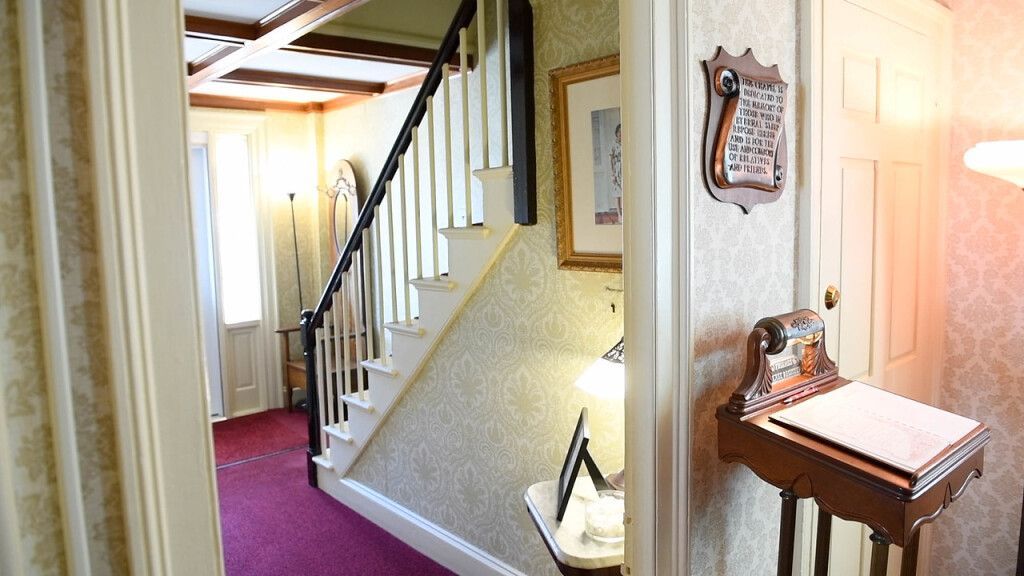 a hallway with stairs and a desk in the middle