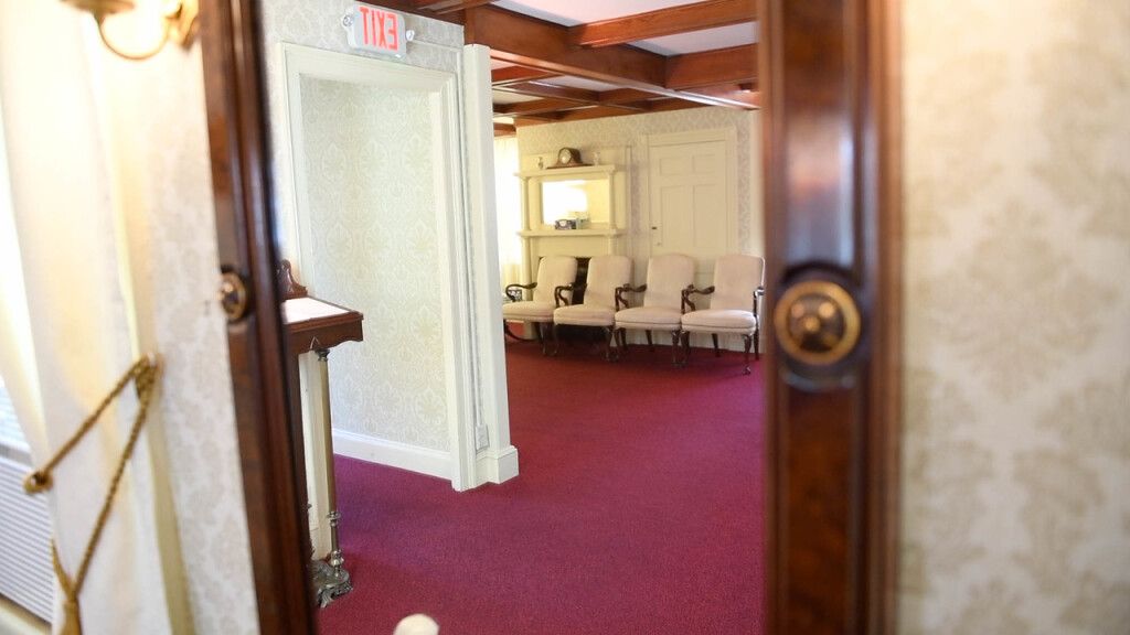 a doorway leading to a waiting room with chairs and a red carpet .