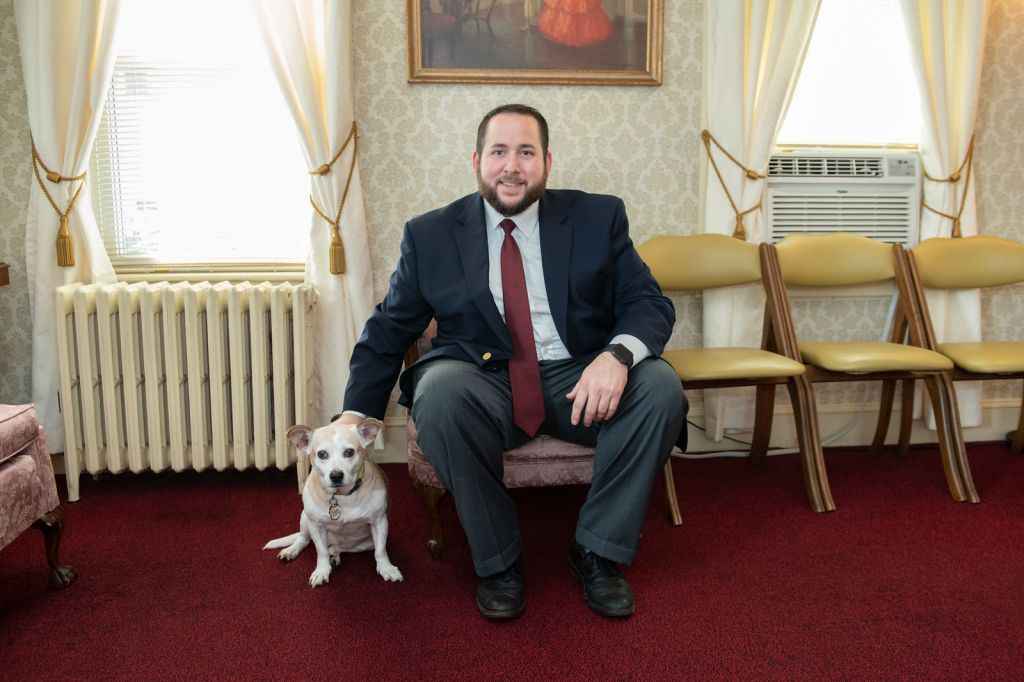 a man in a suit and tie is sitting on a couch with his dog .