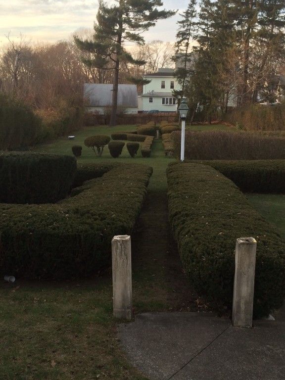 a garden with a white house in the background