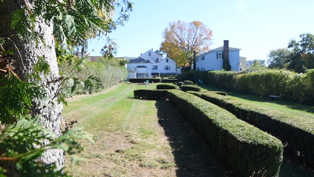a white house is behind a maze of hedges