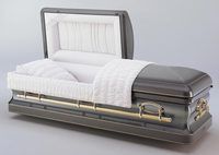a black coffin with the lid open and a white blanket on it .