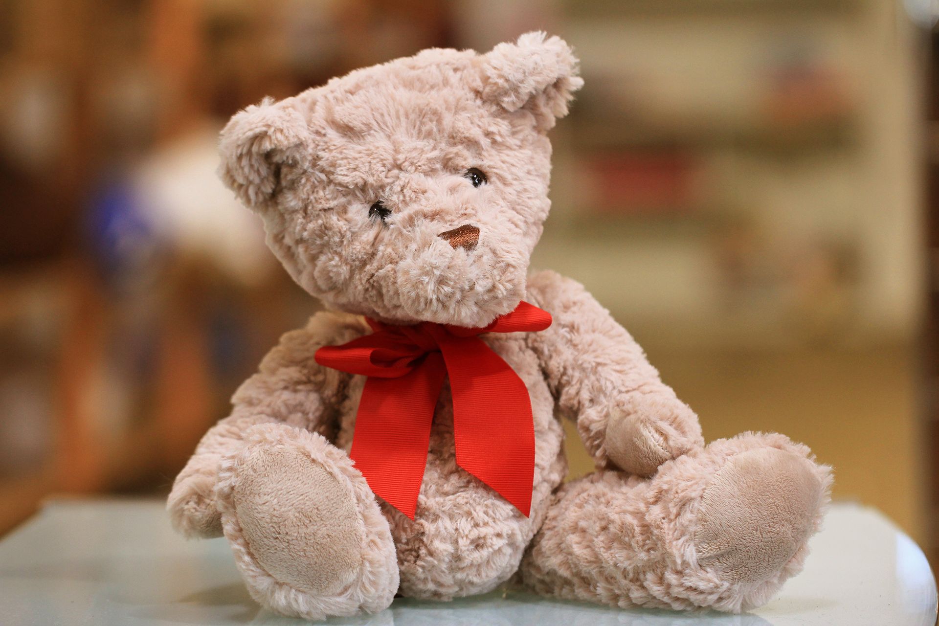 a teddy bear with a red bow is sitting on a table .