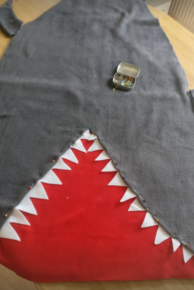 large fabric shark blanket on table ready to sew with tin of pins