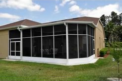 A house with a screened in porch and a lawn in front of it.
