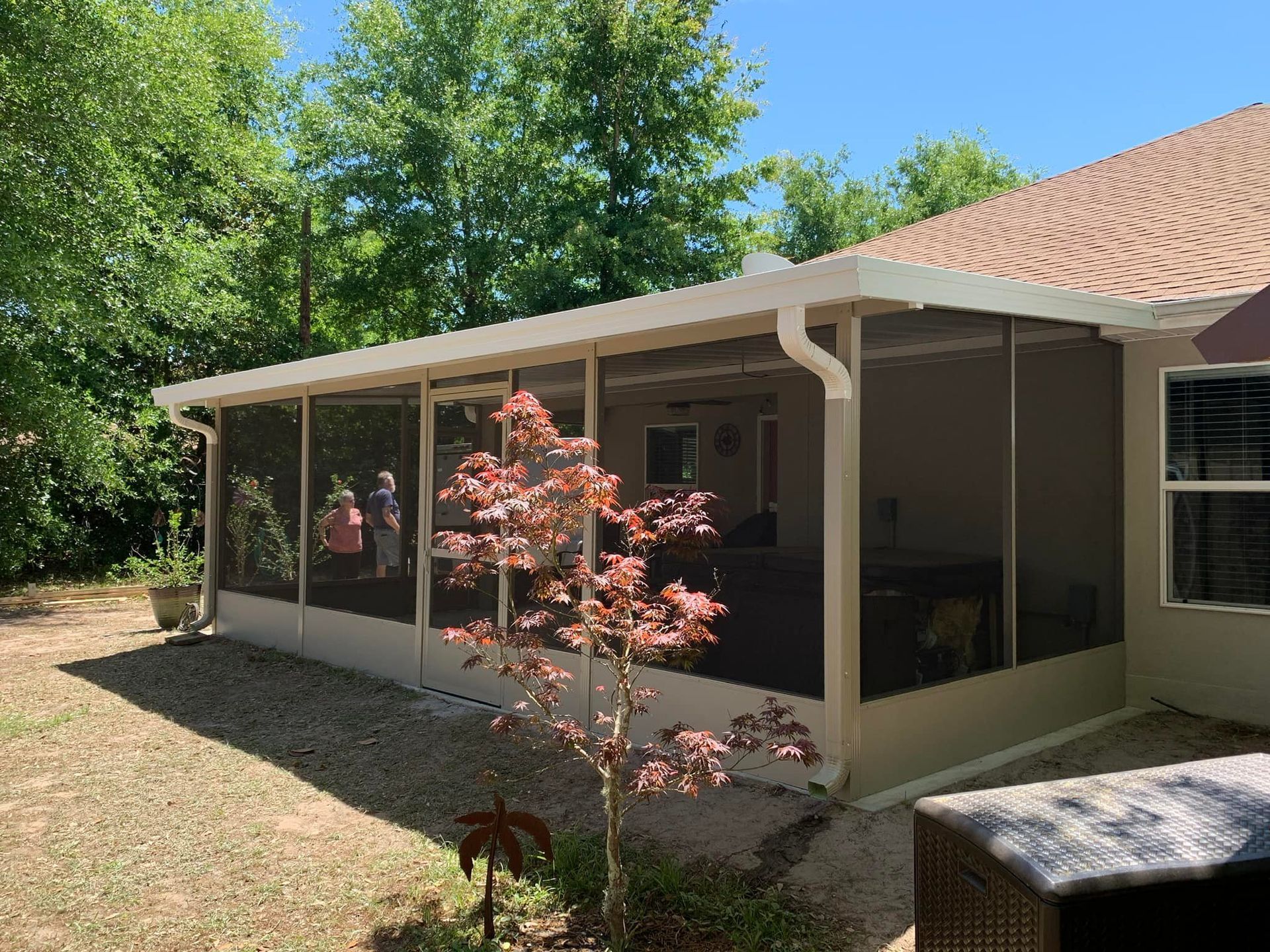 There is a screened in porch in the backyard of a house.