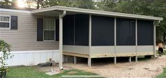 A mobile home with a screened in porch and a driveway.