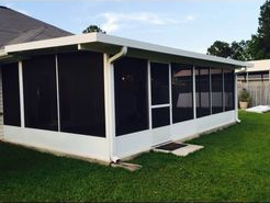 A house with a screened in porch in the backyard.