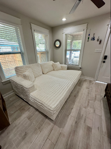 A white couch is sitting in a living room next to a window.