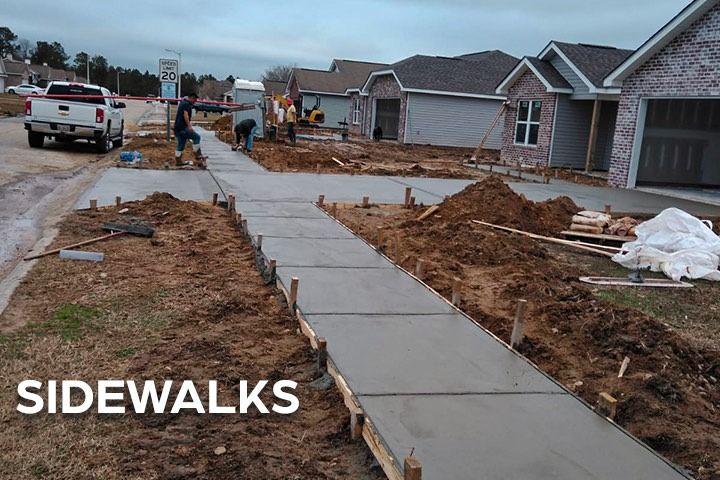 A sidewalk is being built in front of a row of houses.