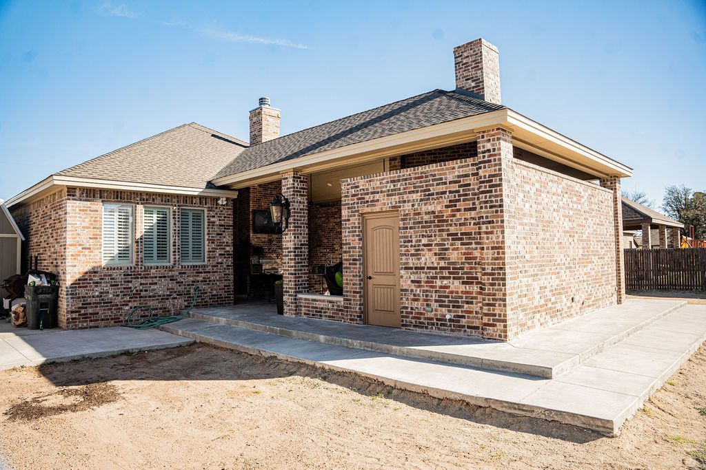 Brick house with a small front porch and walkway on a sunny day.