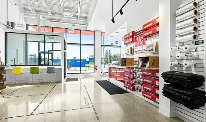 Bright retail space with packaging supplies. White walls, red displays, open window to the exterior.