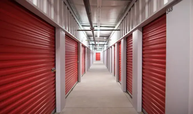 Red storage unit doors line a long, narrow hallway.