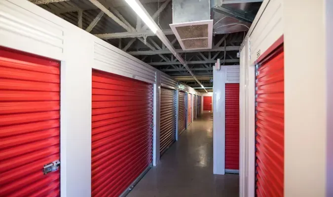 Storage units with red doors along a white-trimmed hallway.