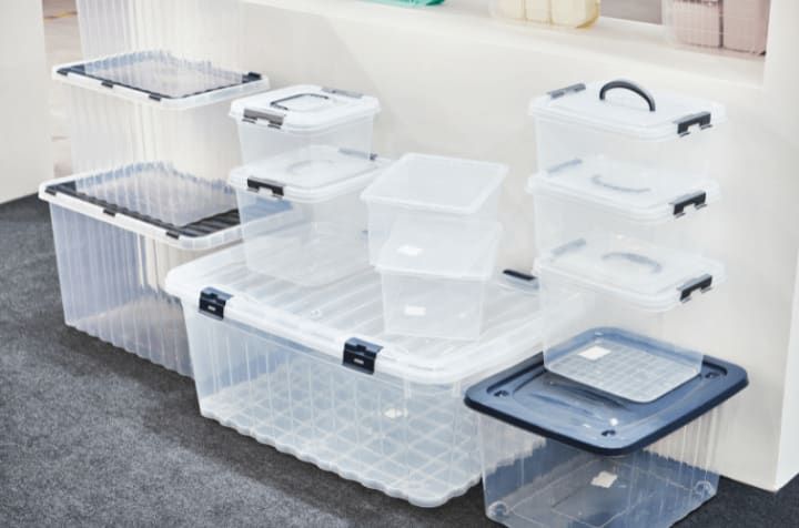 Clear plastic storage bins of various sizes, with black latches and lids, displayed indoors.